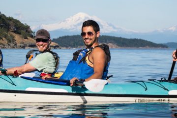 smiling kayakers with mountains behind